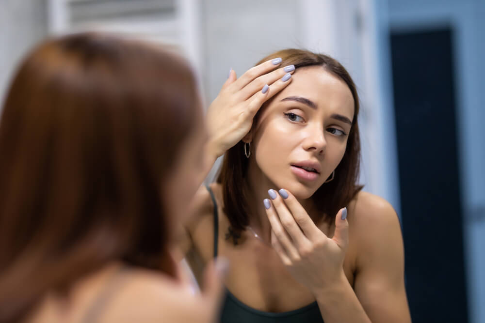 Woman looking at skin in mirror