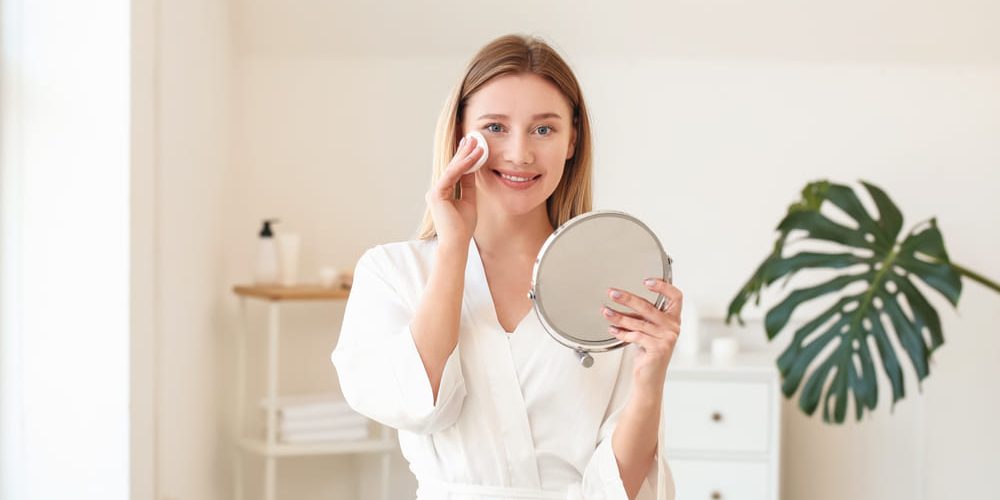 Woman cleansing face in mirror