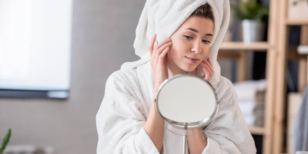 woman looking at skin in mirror