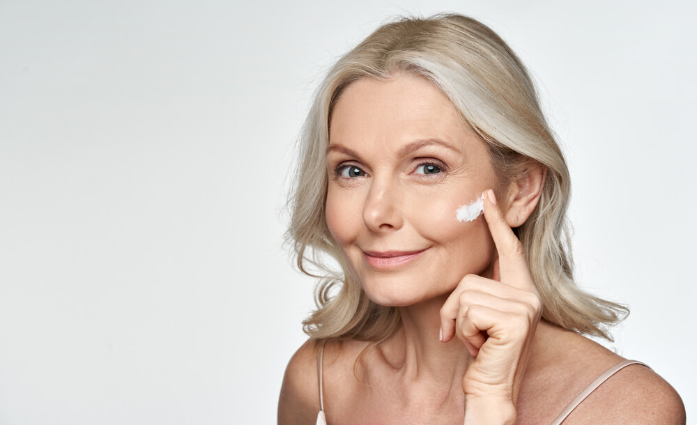 mature woman applying moisturizer