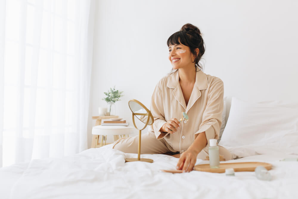 woman sitting on bed doing skincare