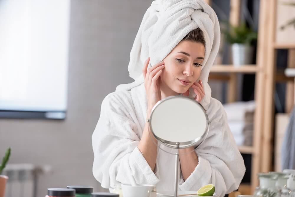 woman looking at skin in mirror